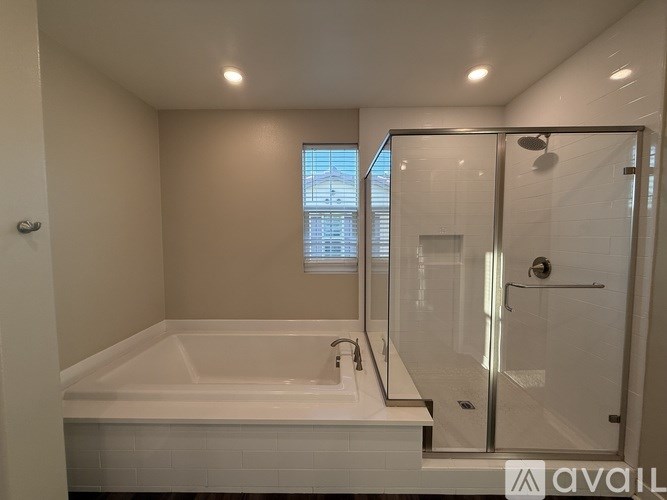 A white bathtub in a bathroom with a glass shower door.