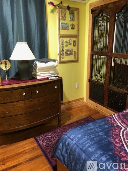 A bedroom with a bed, dresser, and a window with a view of a gate.