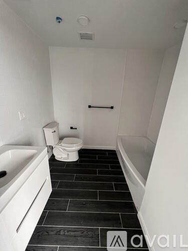 A white bathroom with black tiles and a toilet.
