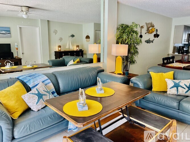 A living room with a blue couch and yellow pillows.