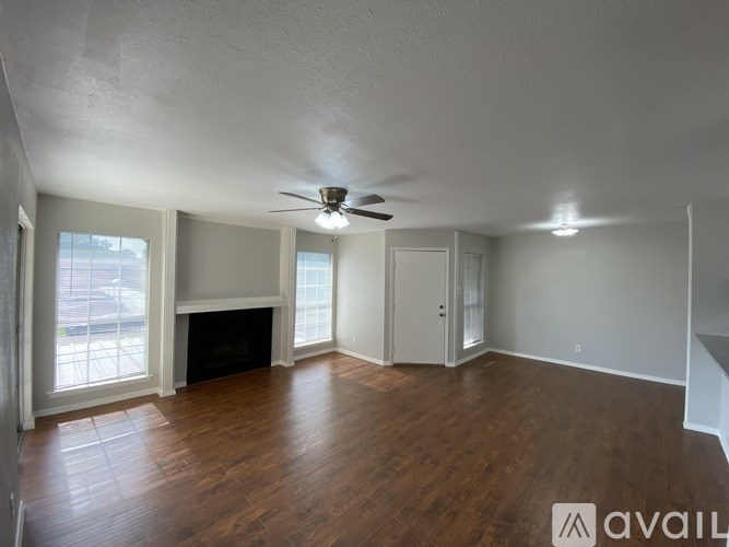A spacious room with wood flooring and a ceiling fan.