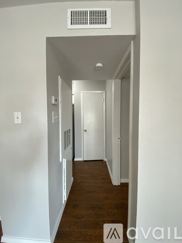 A hallway with a white wall and a door on the right.