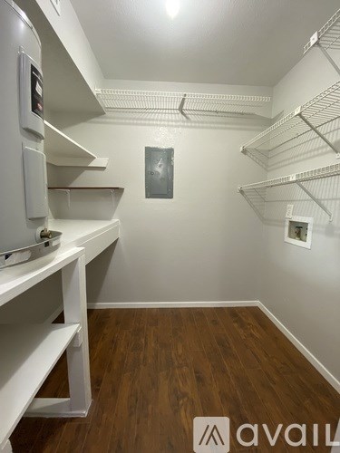 A walk in closet with white shelving and wood floors.