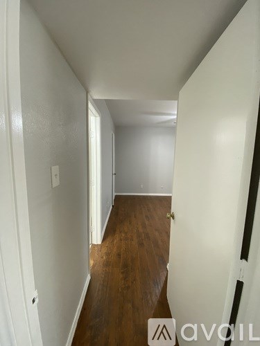 A hallway with a wooden floor and white walls.