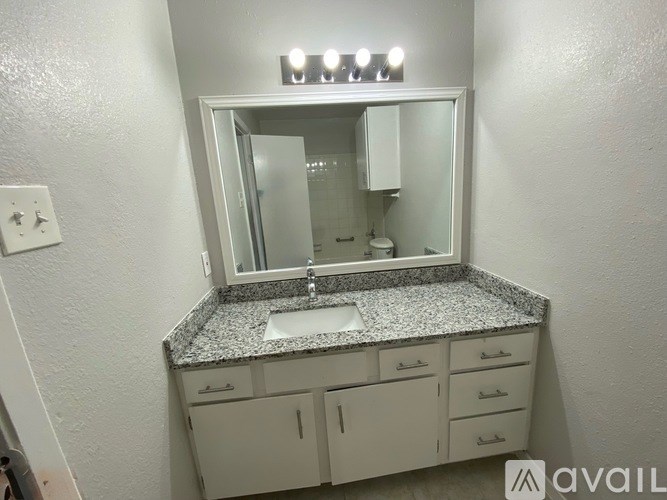 A bathroom with a granite countertop and a mirror above a sink.