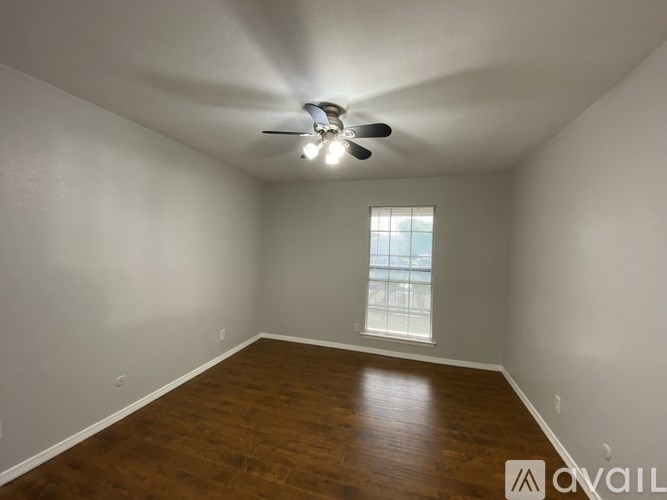 A room with a ceiling fan and wooden flooring.