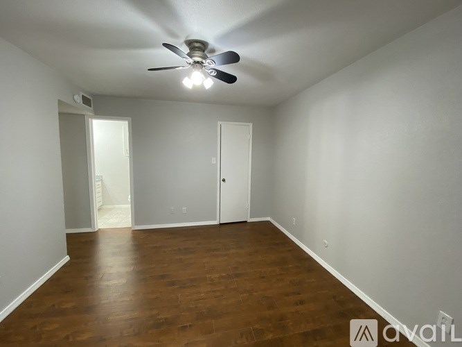 A room with a ceiling fan and wooden flooring.