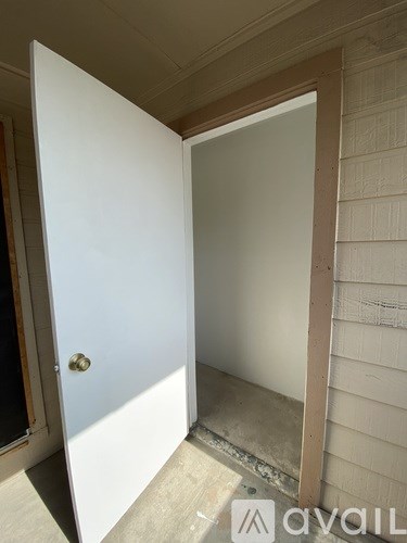 A white door is open to a room with a white wall.