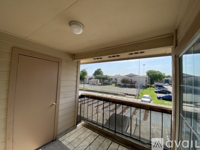 A balcony with a view of a parking lot and buildings.