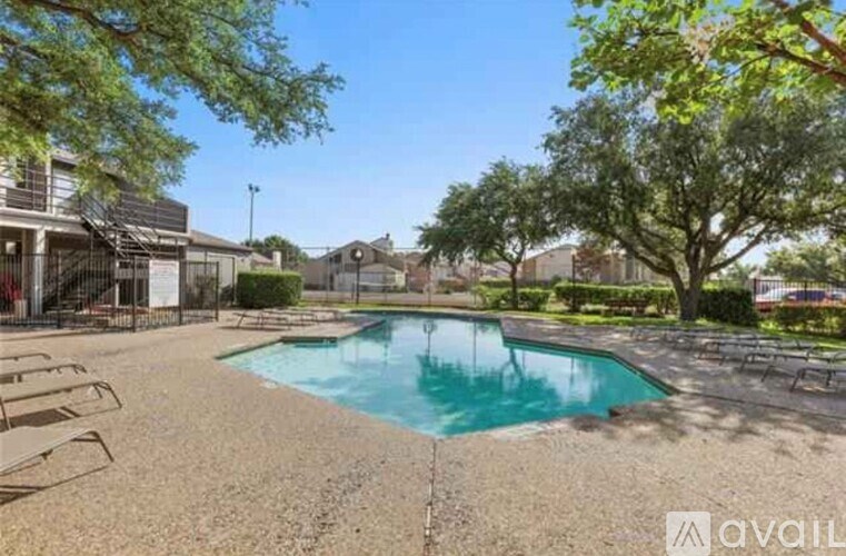 A pool surrounded by trees and a building in the background.
