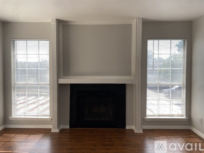 A living room with a fireplace and two windows.