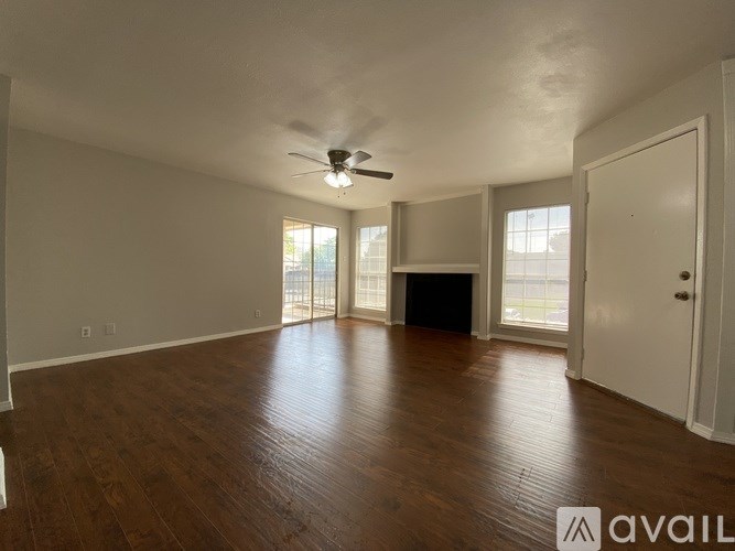 A spacious room with wooden floors and a ceiling fan.