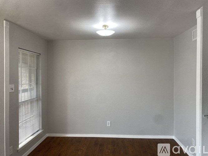 A room with a window and a wooden floor.
