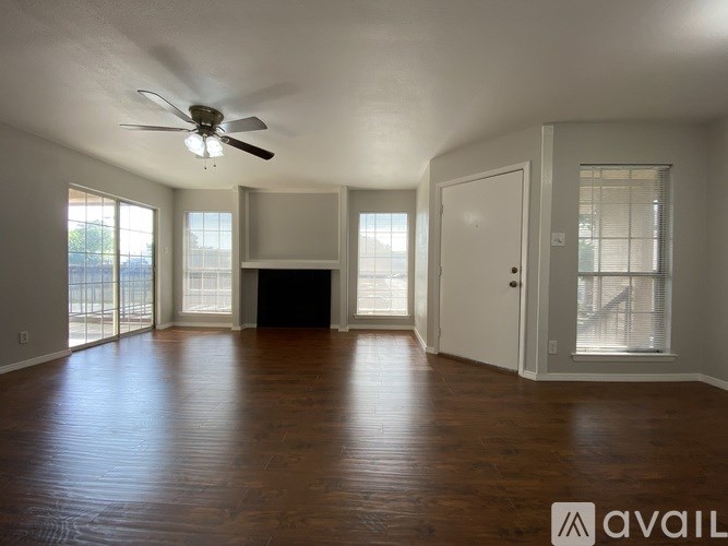 A spacious room with a ceiling fan and wooden flooring.
