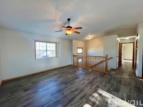 A spacious room with a ceiling fan and wooden flooring.