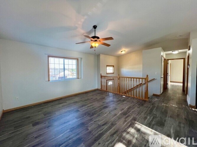 A spacious room with a ceiling fan and wooden flooring.