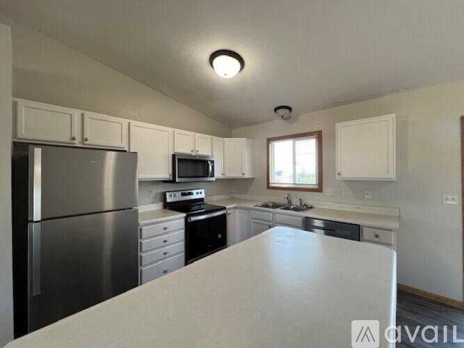 A kitchen with a stainless steel refrigerator and white countertops.