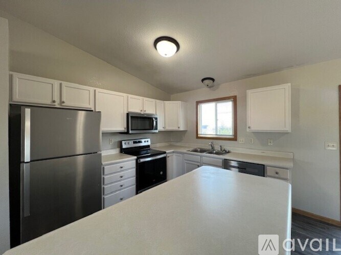 A kitchen with a stainless steel refrigerator and white countertops.