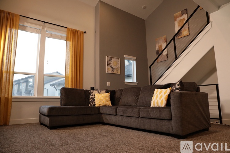 A living room with a brown couch and a staircase.