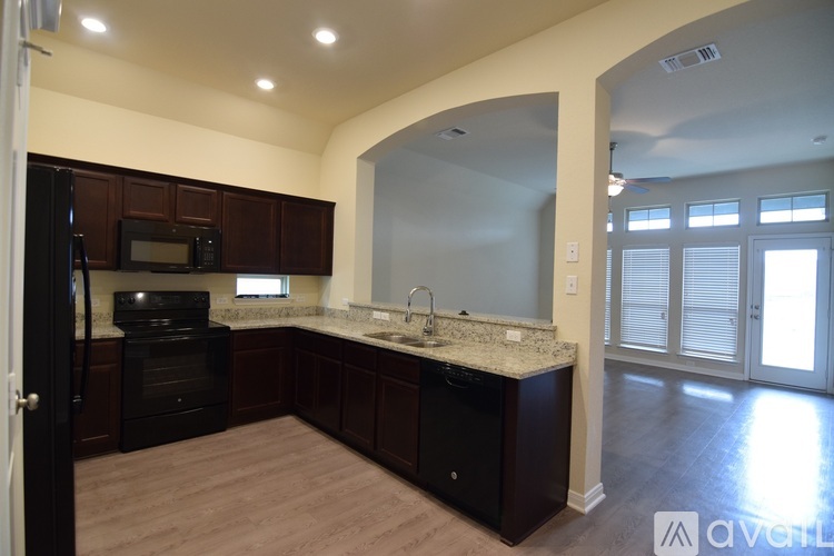 A kitchen with dark wood cabinets and a black dishwasher.