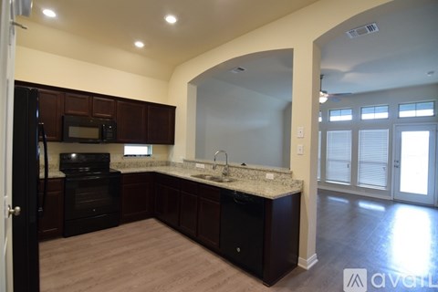 A kitchen with dark wood cabinets and a black dishwasher.