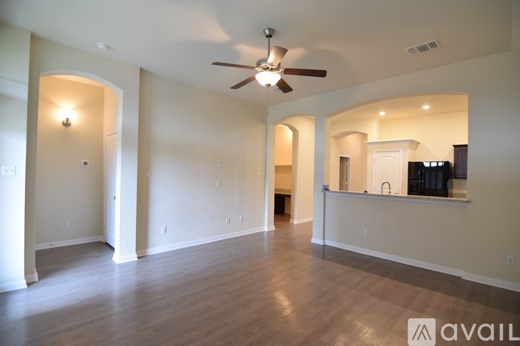 A spacious living room with a ceiling fan and hardwood flooring.