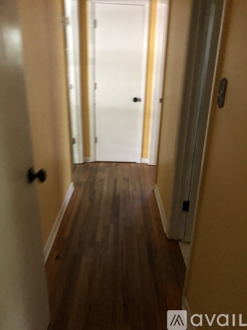 A hallway with a wooden floor and white walls.
