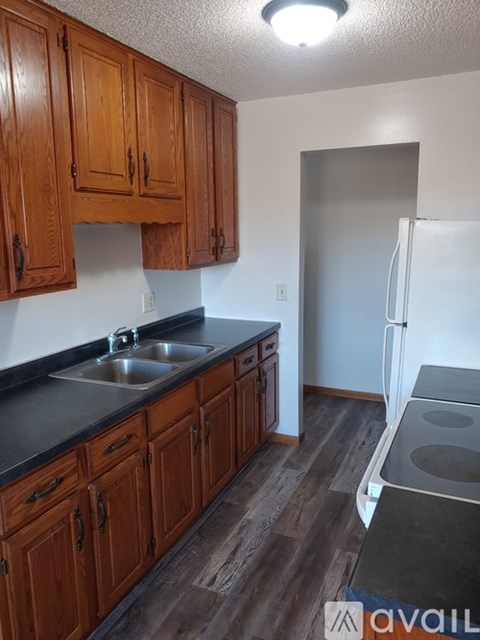 A hallway with a black door and a light switch on the wall.