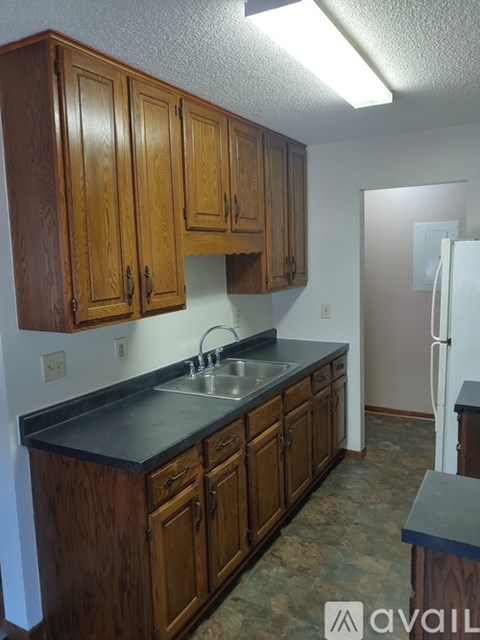 A kitchen with wooden cabinets and a black counter top.