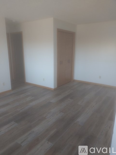 A room with wooden flooring and a window with blinds.