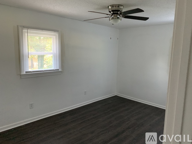 A room with a ceiling fan and a window with blinds.