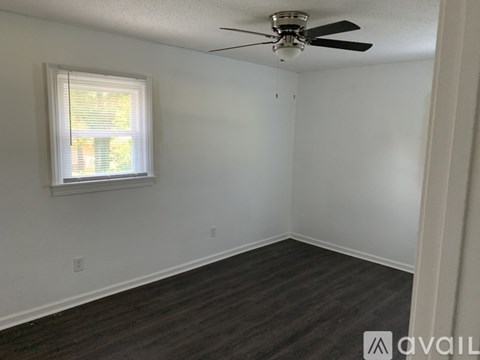 A room with a ceiling fan and a window with blinds.