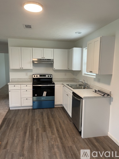 A kitchen with white cabinets and a wooden floor.