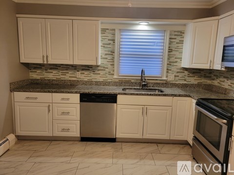 A kitchen with white cabinets and a black dishwasher.