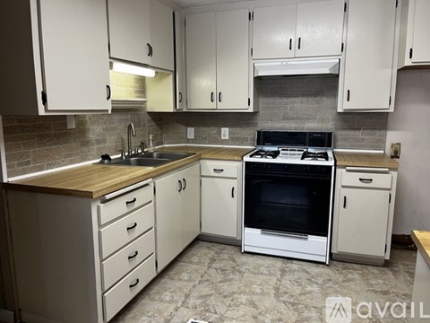 A kitchen with white cabinets and a wooden countertop.