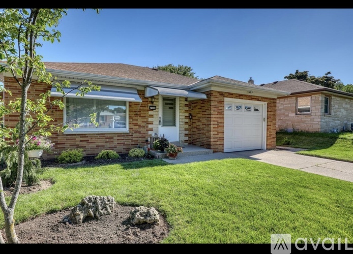 A house with a well-maintained lawn and a tree in front.