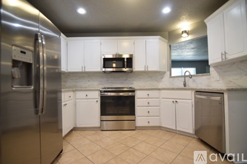 A kitchen with white cabinets and a stainless steel refrigerator.
