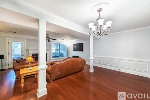 A living room with a brown couch and a chandelier.
