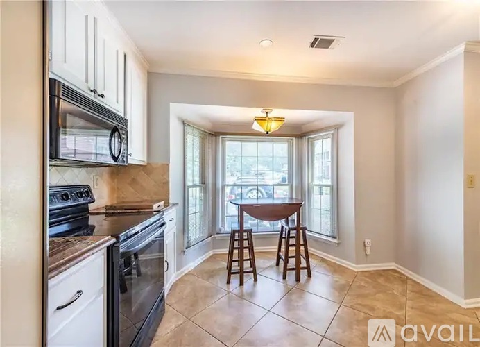 A kitchen with a table and chairs by a window.