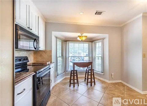 A kitchen with a table and chairs by a window.