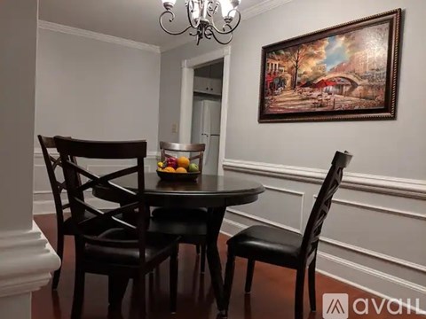 A dining room with a table set for two and a painting on the wall.