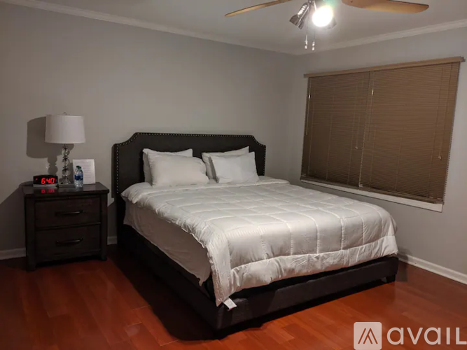 A bedroom with a large bed and a nightstand with a lamp.
