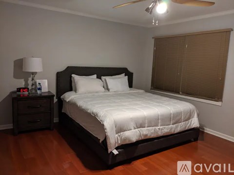 A bedroom with a large bed and a nightstand with a lamp.