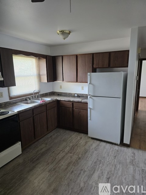 A kitchen with a white fridge and brown cabinets.