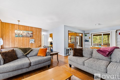 A living room with a grey couch and a wooden wall.
