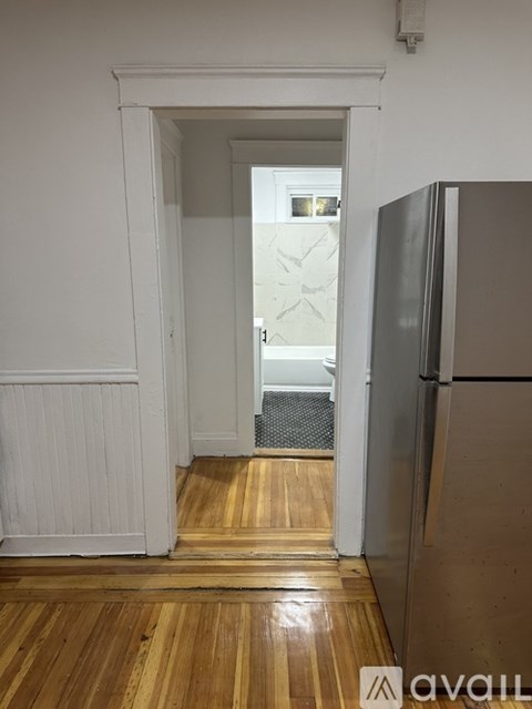 A kitchen with a refrigerator and a doorway leading to another room.
