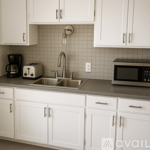 A kitchen with white cabinets and a silver sink.