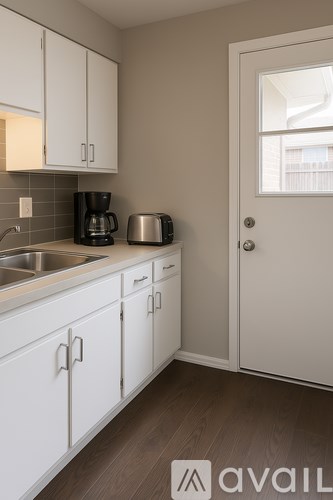 A kitchen with white cabinets and a stainless steel sink.