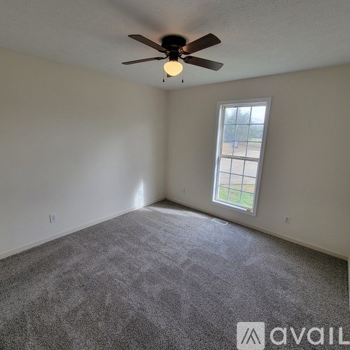 A room with a ceiling fan and carpeted floor.