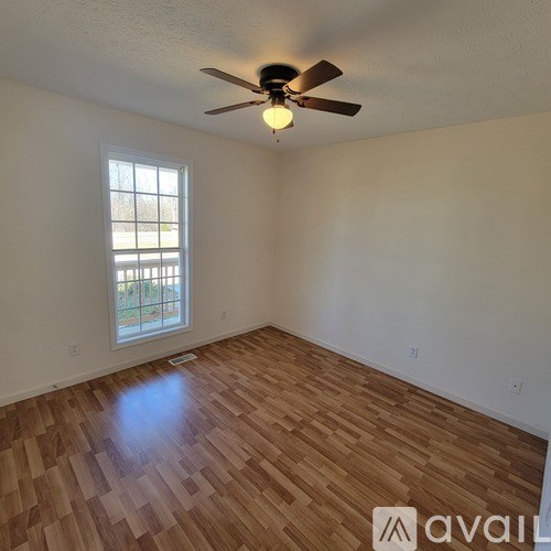 A room with wooden flooring and a ceiling fan.
